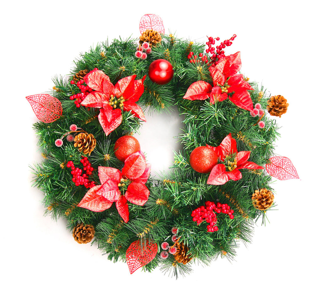 A decorated artificial Christmas wreath with green pine and spruce tips, red flowers, baubles, and leaf branches.